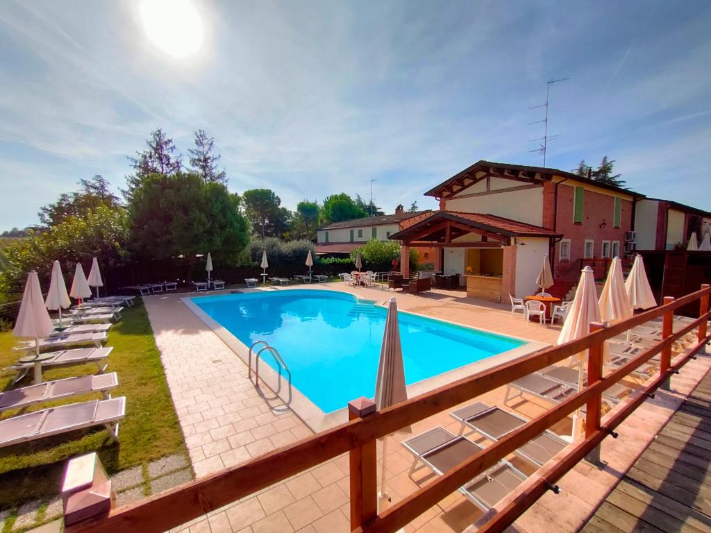 ein großer Pool mit Stühlen und Sonnenschirmen in der Unterkunft Agriturismo e Cantina La Sabbiona in Faenza