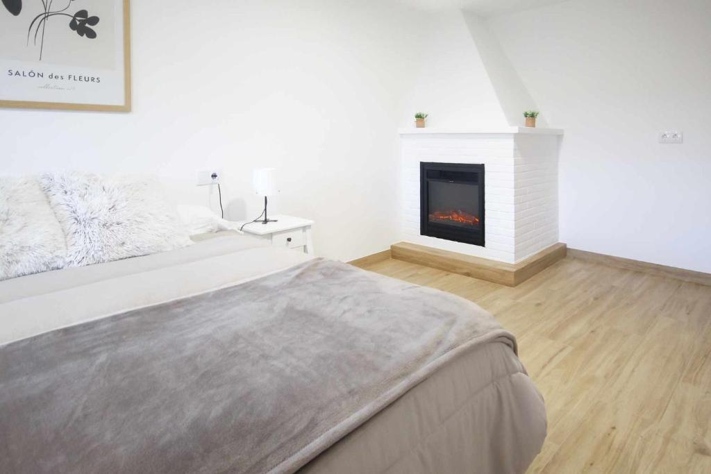 Dormitorio blanco con cama y chimenea en AG Casa Anema 10 huéspedes a 2km de la playa Razo, en A Coruña