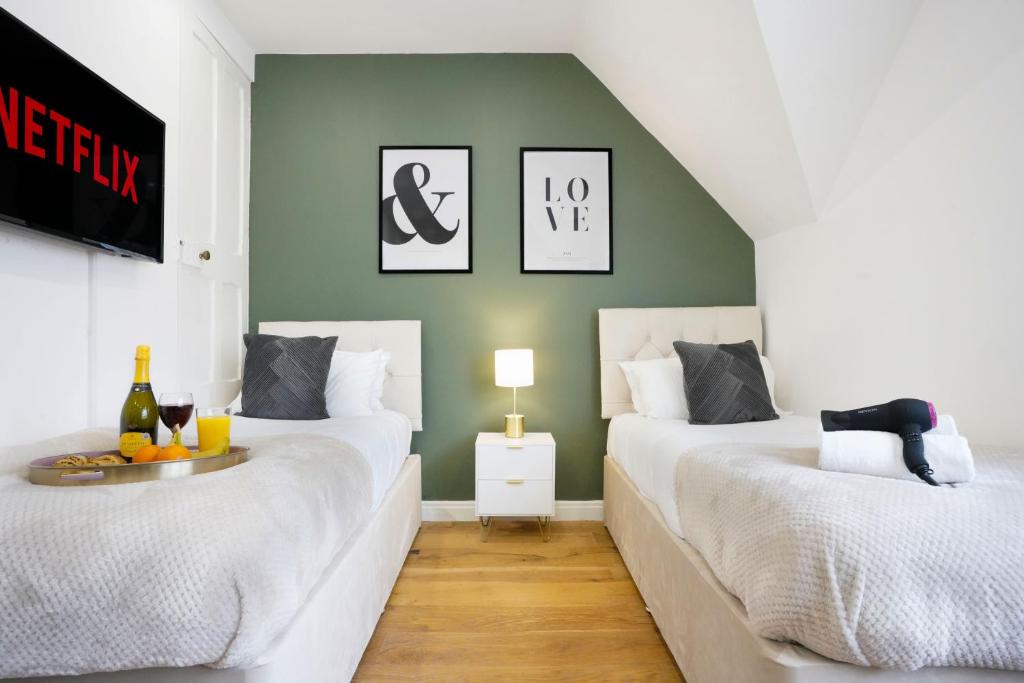 twee bedden in een kamer met een groene muur bij Central Buckingham Apartment #9 with Free Parking, Pool Table, Fast Wifi and Smart TV with Netflix by Yoko Property in Buckingham