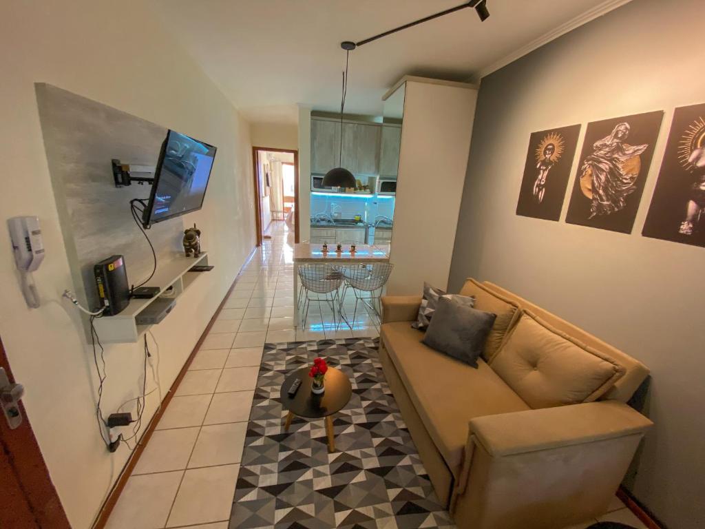 uma sala de estar com um sofá e uma mesa em Apartamento de frente com sacada no centro de Capão da Canoa em Capão da Canoa