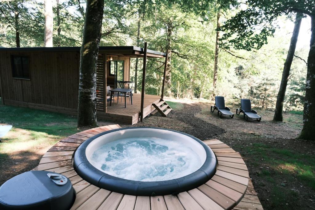 uma banheira de hidromassagem situada num deque de madeira num quintal em Lodge avec SPA privatif - Foret et Lac em Liginiac