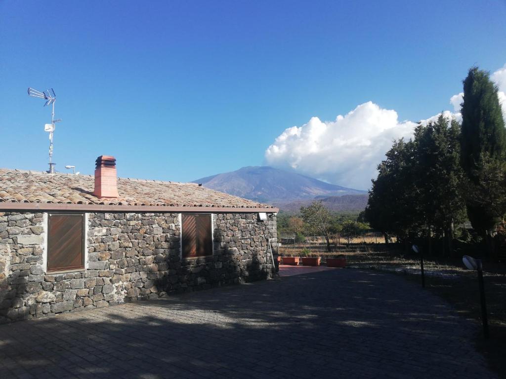 a stone house with a mountain in the background at Soggiorno contrada difesa in Maletto