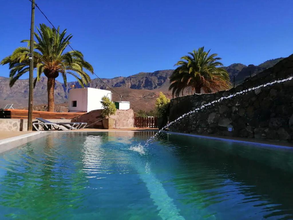 einen Pool mit einem Wasserspiel in einem Hinterhof mit Palmen in der Unterkunft La casa vieja de la Montaña in Santa Lucía