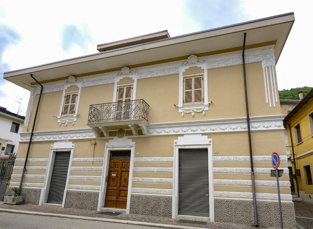 a yellow house with a balcony on a street at Villino Liberty nel cuore della Marsica in Luco neʼ Marsi