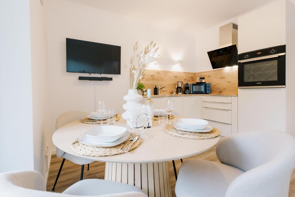 a white kitchen with a table with chairs and a tv at Küsten Suite de See - Suite 1 direkte Deichlage, Terrasse, 53qm in Greetsiel