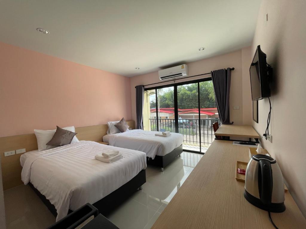 Habitación de hotel con 2 camas y TV en โรงแรมนิยม เอสทีเอ็น 2 - Niyom STN 2 Hotel, en Ban Phue