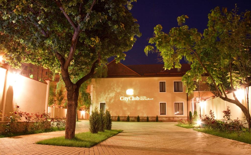 ein Gebäude in der Nacht mit Bäumen im Vordergrund in der Unterkunft CityClub Hotel in Tiraspol