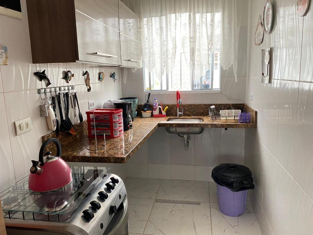 cocina con fogones y hervidor de agua rojo en Casa da Lú - Praia e Piscina en Praia Grande