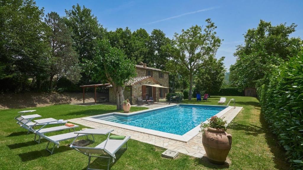 uma piscina com espreguiçadeiras e uma casa em La Mita em Cortona