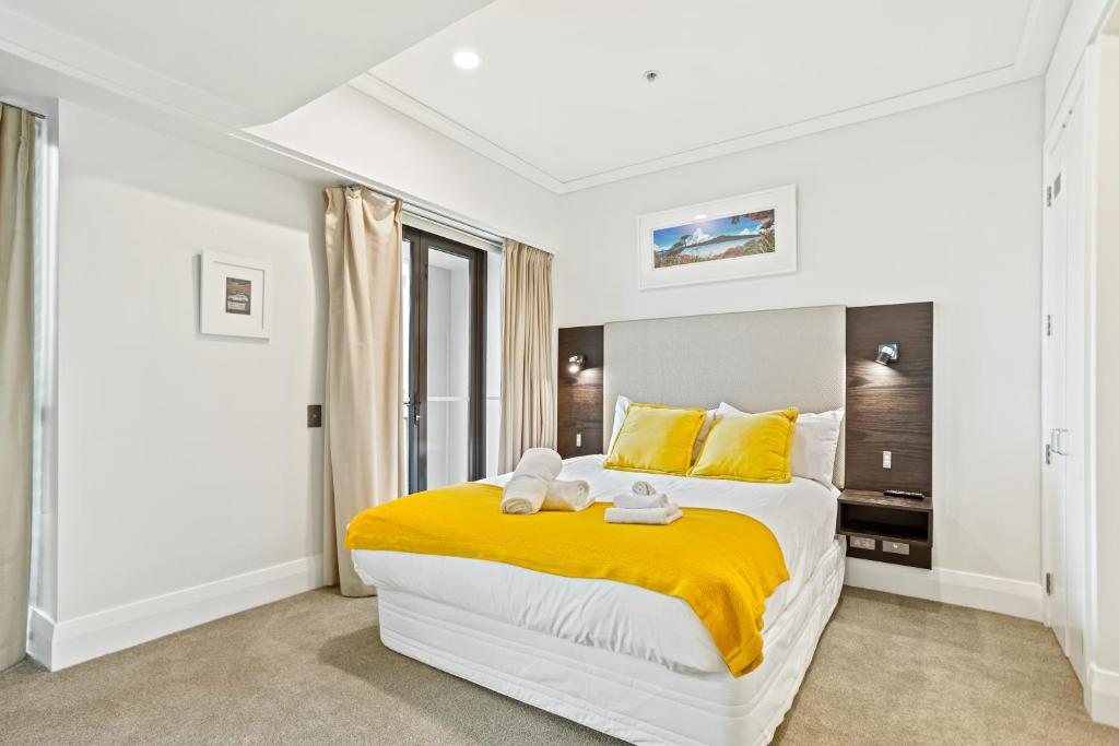 sypialnia z dużym łóżkiem z żółtą pościelą i żółtymi poduszkami w obiekcie Fabulous Corner Apartment w/ Dazzling Harbour View w Auckland