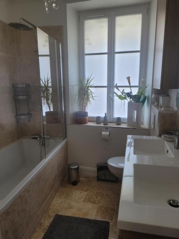bagno con 2 lavandini, vasca e servizi igienici di Petite maison avec jardin et cheminée 