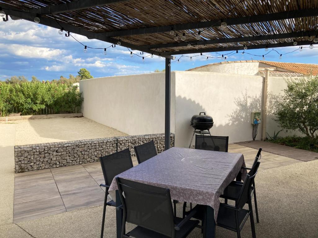- une table et des chaises sur une terrasse avec barbecue dans l'établissement Maison accueillante à Saintes-Maries-de-la-Mer avec jardin clos, à Saintes-Maries-de-la-Mer