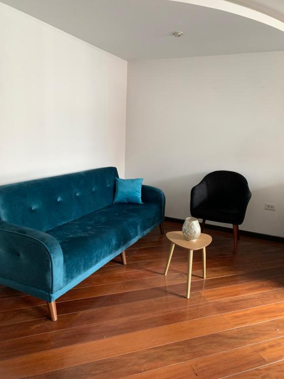 uma sala de estar com um sofá azul e uma mesa em Suite de lujo Quito em Quito