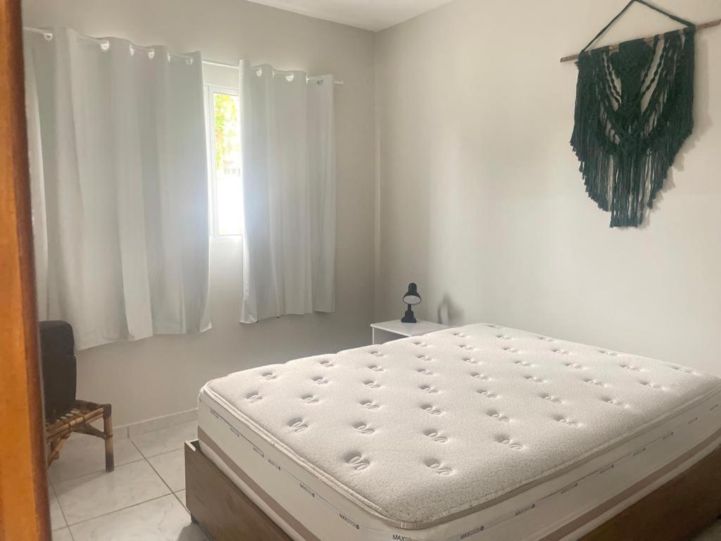 ein weißes Schlafzimmer mit einem Bett und einem Fenster in der Unterkunft Condomínio Moradas da Vila in Imbituba