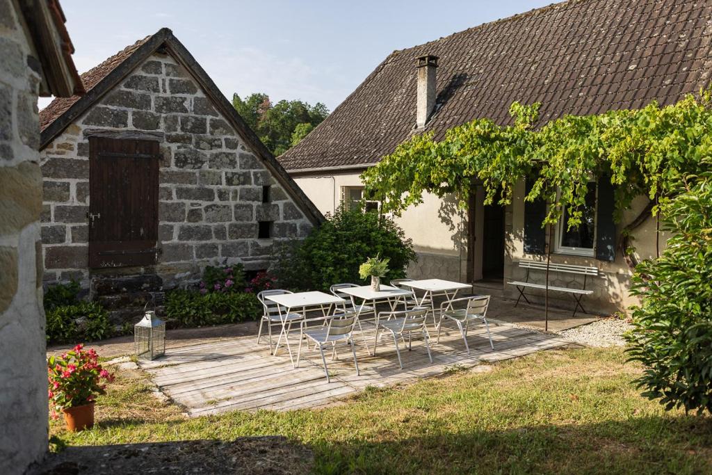 a patio with tables and chairs in front of a building at Gîte de la Gare aux Fleurs 