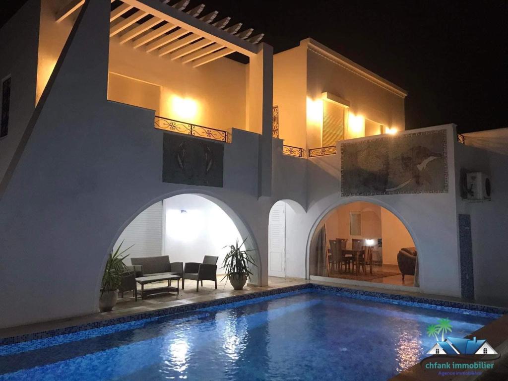 a villa with a swimming pool at night at Villa Amine Flouka in Houmt Souk