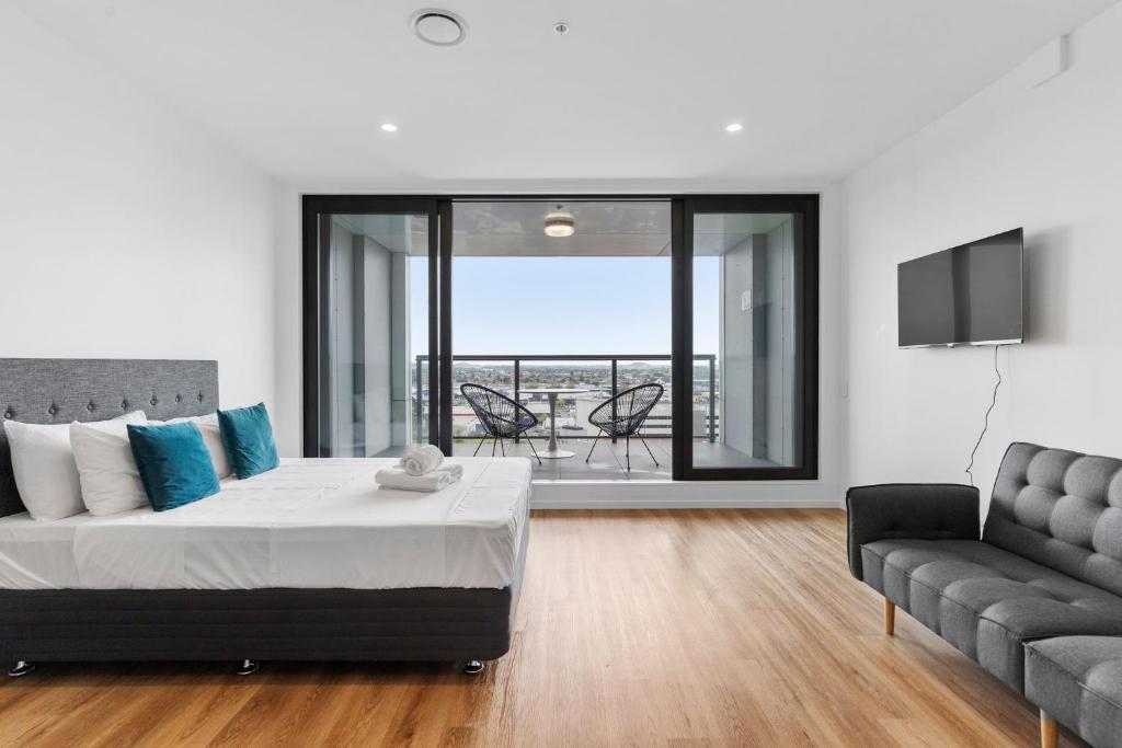 um quarto com uma cama, um sofá e uma televisão em Manukau Studio Apartments em Auckland