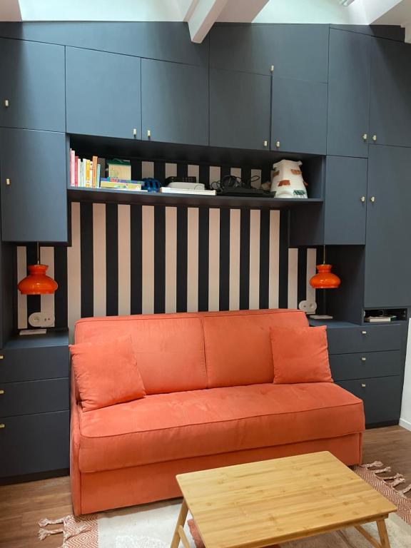 an orange couch in a living room with blue cabinets at Studio Calme Batignolles in Paris