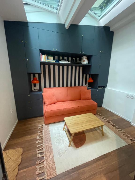 a living room with an orange couch and a table at Studio Calme Batignolles in Paris