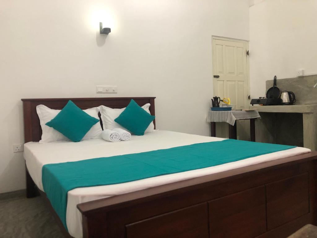 una camera da letto con un letto grande con cuscini verdi e bianchi di Waves a Hikkaduwa
