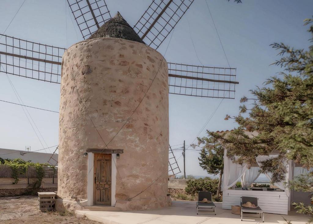 a stone windmill with two chairs in front of it at Molino Sa Miranda - Formentera Break in Sant Francesc Xavier