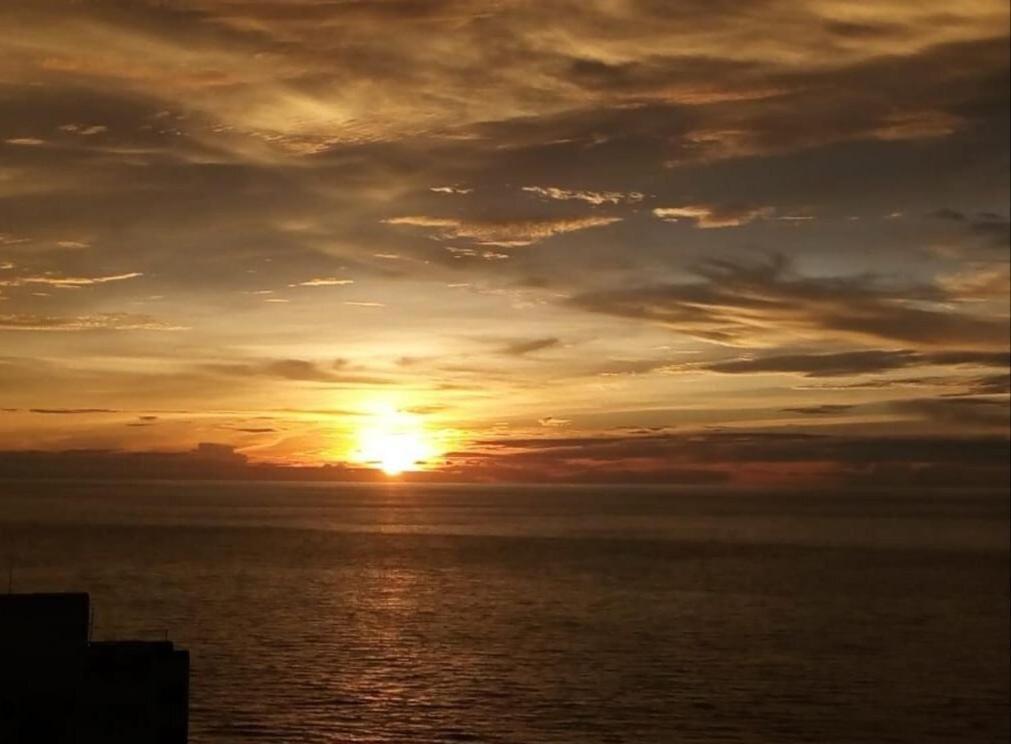 una puesta de sol sobre el océano con el sol en el cielo en Hermoso edificio de frente al mar, en Cartagena de Indias