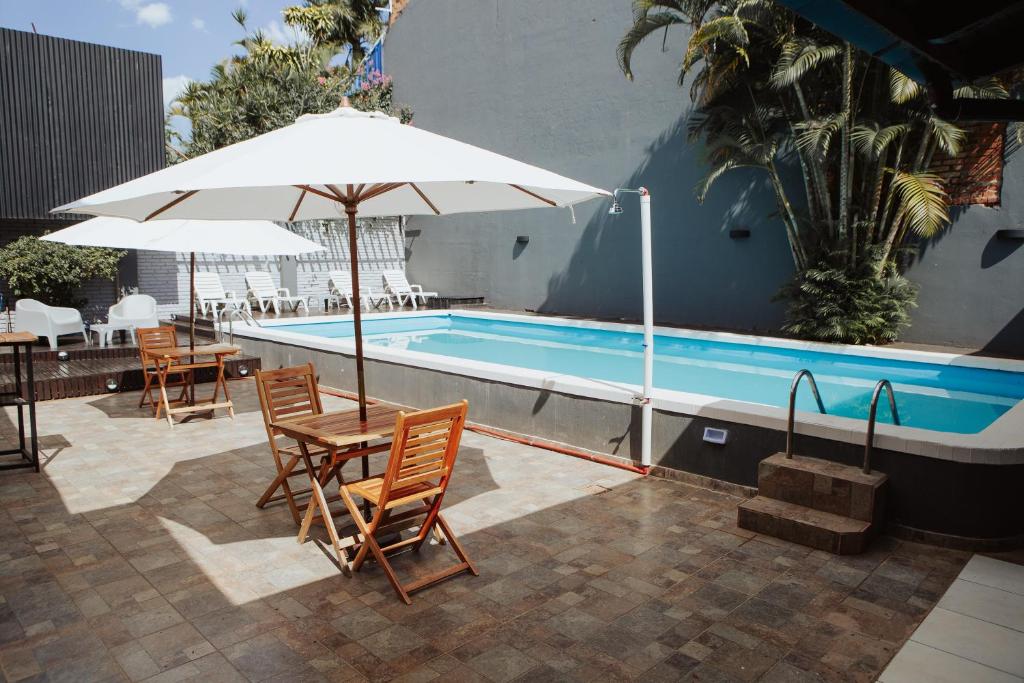 a pool with chairs and a table and an umbrella at ISONDU Suites & Breakfast in Puerto Iguazú