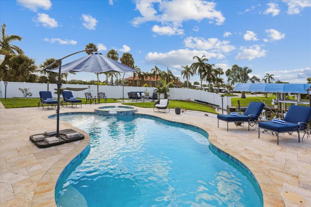 a swimming pool with blue chairs and an umbrella at Royal Blue Dreams flexible rental near Anna Maria Island in Bradenton