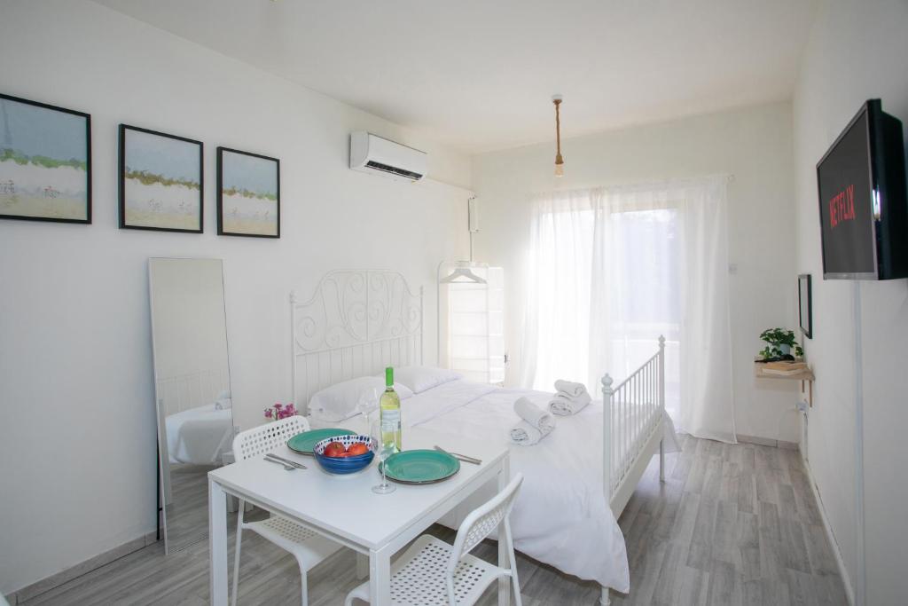 a white table and chairs in a white room at Palmove Makenzie Studio 4 in Larnaca