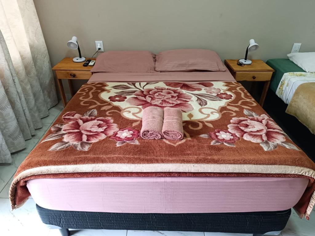 een bed met twee paar roze sokken erop bij Hotel Village del Sol in Puerto Iguazú