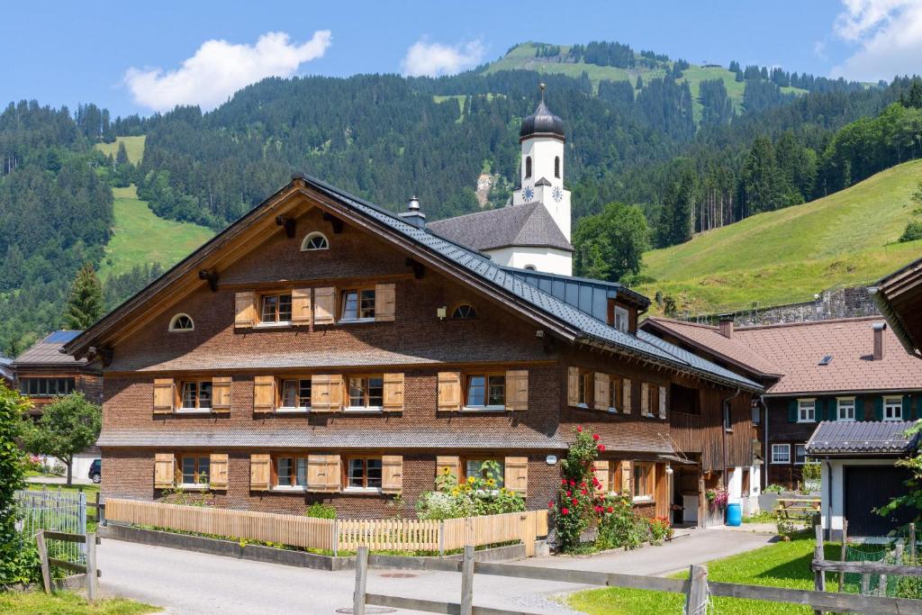 ein großes Holzgebäude mit einem Uhrturm auf einem Berg in der Unterkunft Ferienhaus Nigsch in Schoppernau