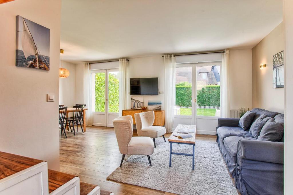 sala de estar con sofá azul y sillas en Sweet Home - PiscineTennis - Deauville, en Deauville
