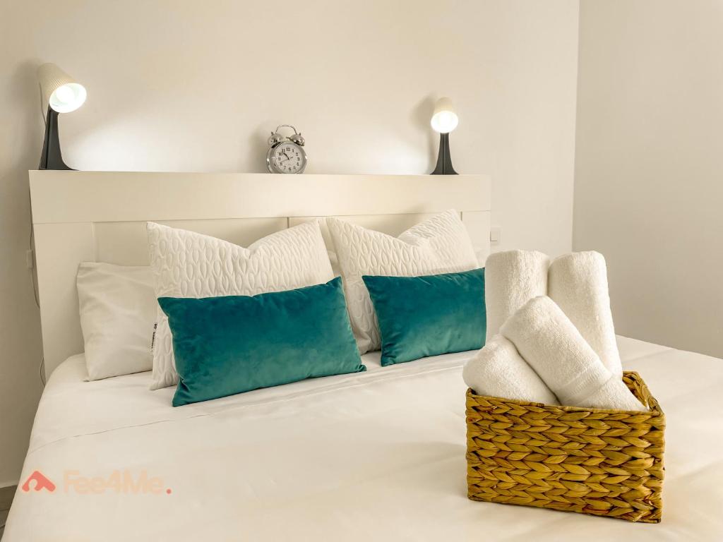 uma cama branca com almofadas brancas e um cesto em Fee4Me Gáldar, a pocos minutos del valle de Agaete em Gáldar