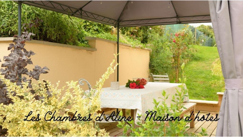 stół pod parasolem w ogrodzie w obiekcie Les Chambres D'Aline w mieście Conches