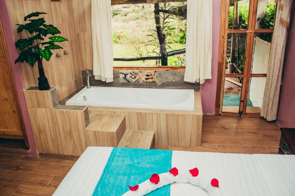 a bathroom with a tub and a bed and a window at Balcones del Paraíso in Baños