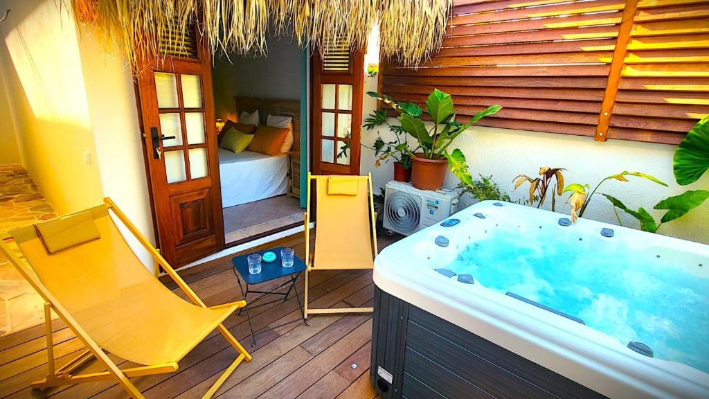 eine Badewanne mit Stuhl und ein Bett in einem Zimmer in der Unterkunft Sweet Payot : Studio avec Spa privé et piscine in Le Lamentin