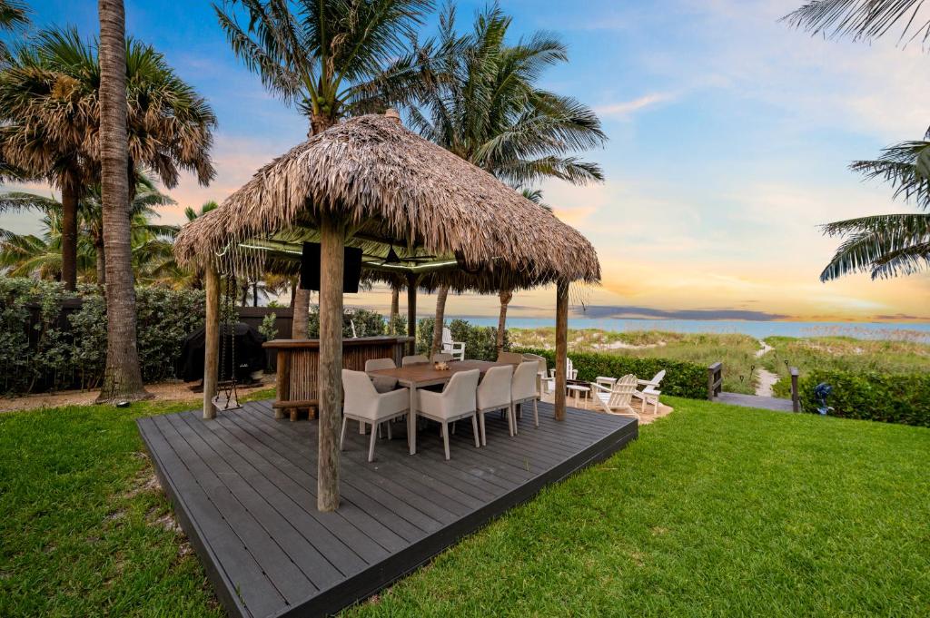 a wooden deck with a table and chairs and a straw umbrella at Vista Del Mar Oceanfront Home Stunning Views Backyard Oasis in Cocoa Beach