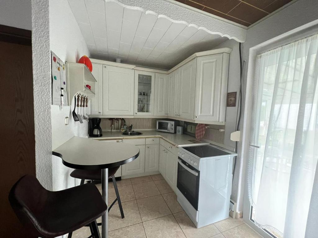 eine Küche mit weißen Schränken, einem Tisch und einem Waschbecken in der Unterkunft Haus Elli 