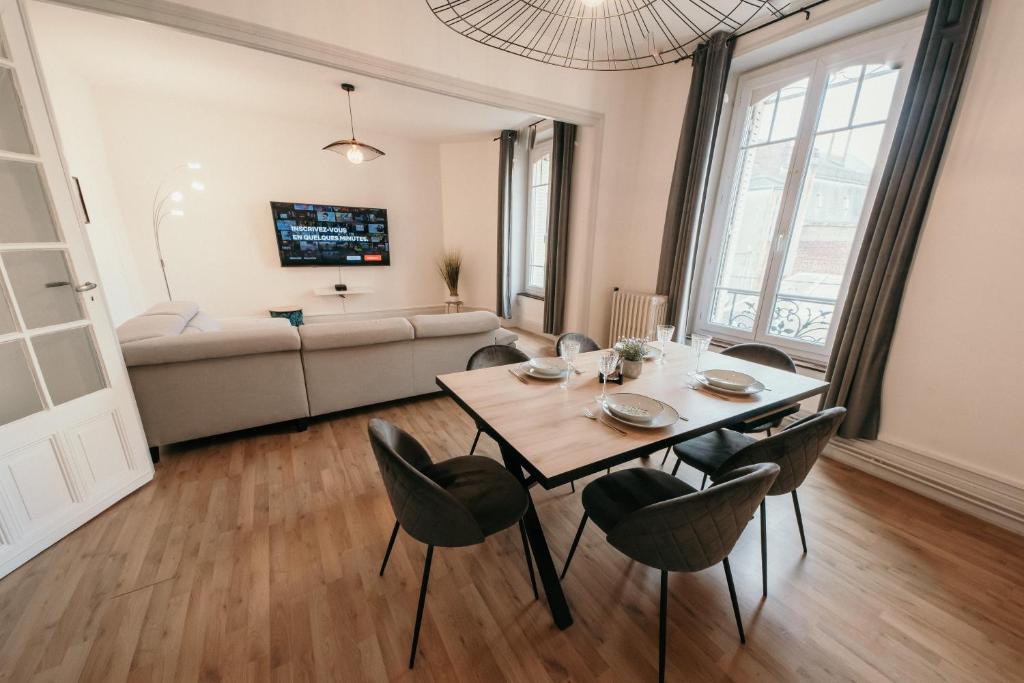 ein Wohnzimmer mit einem Tisch, Stühlen und einem Sofa in der Unterkunft Appartement d'Alexandre hyper centre-ville in Charleville-Mézières