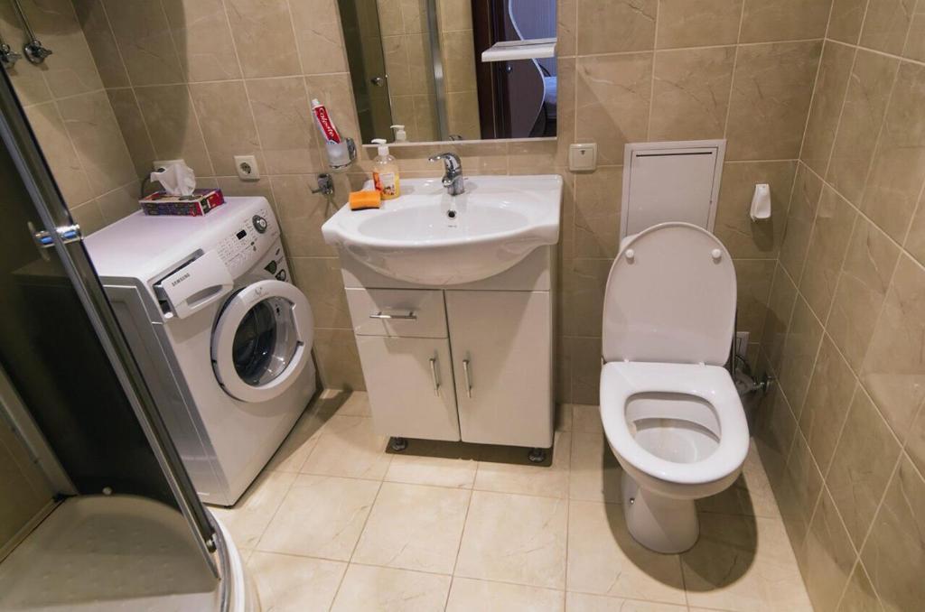 a bathroom with a toilet and a sink and a washing machine at Квартира на березі Дніпра у новому будинку! in Cherkasy