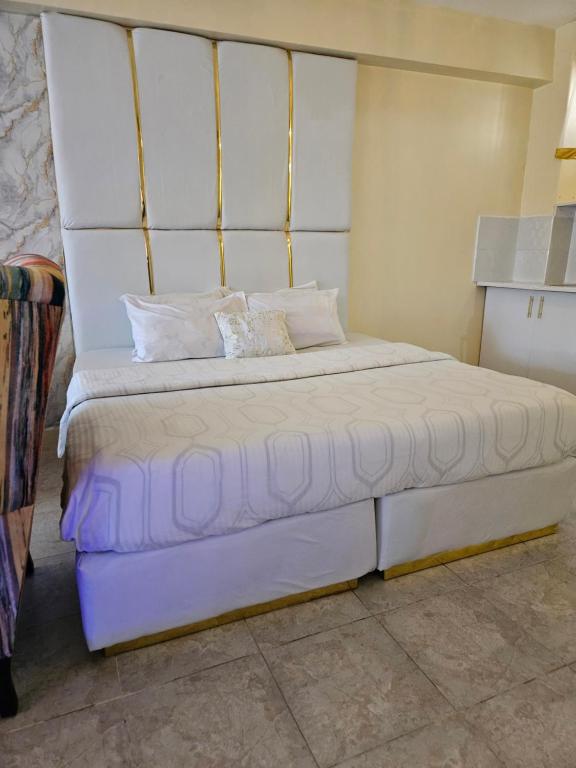 1 dormitorio con 1 cama blanca grande con almohadas blancas en Airport Studio Apartments-JKIA en Nairobi