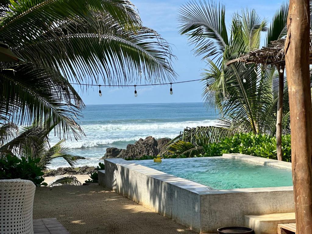 a swimming pool on the beach with the ocean at Quinta Feliz Troncones in Troncones