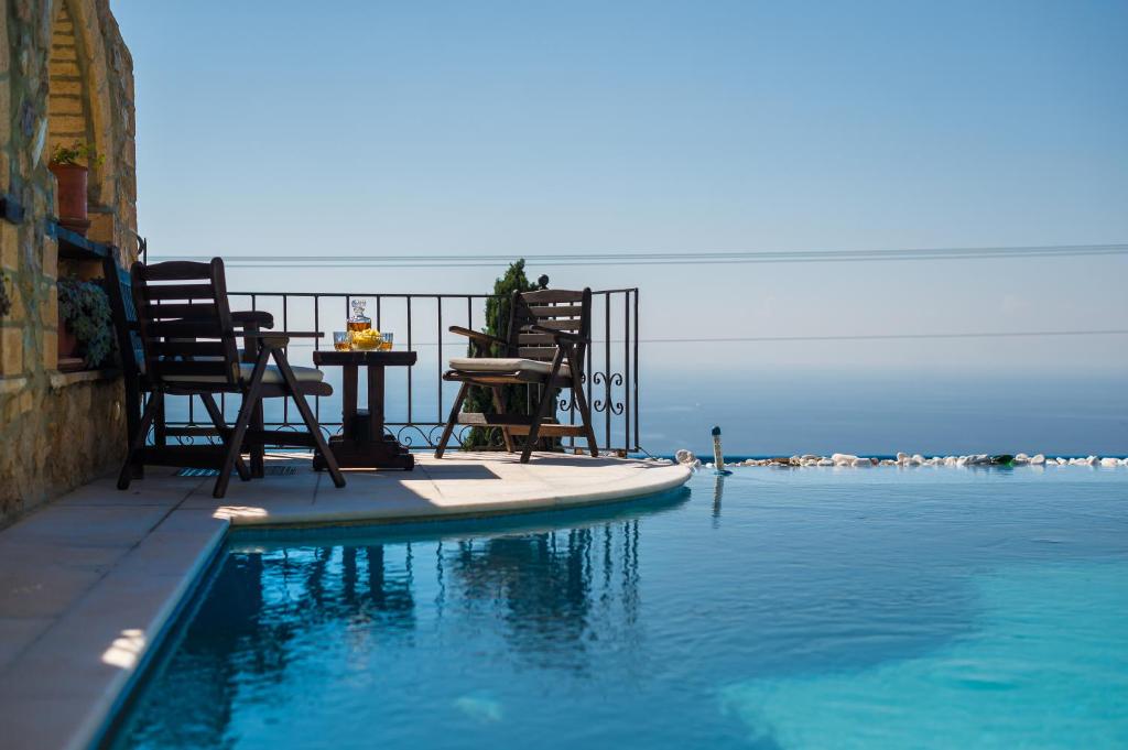 a patio with chairs and a table in the water at Four Seasons Stonework Castle in Lagonissi