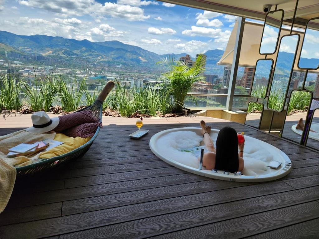 Um par de raparigas deitadas numa banheira num deque. em Diez Hotel Categoría Colombia em Medellín