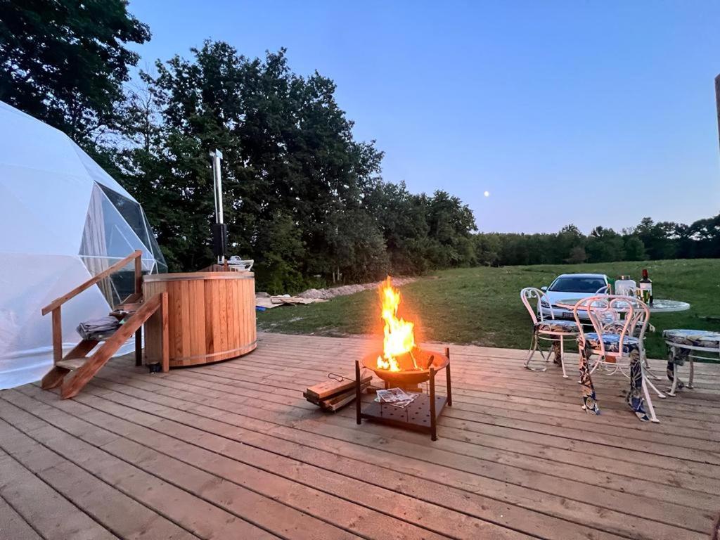 a fire pit on a wooden deck with a tent at Open Sky Glamping Kawartha Dome in Marmora