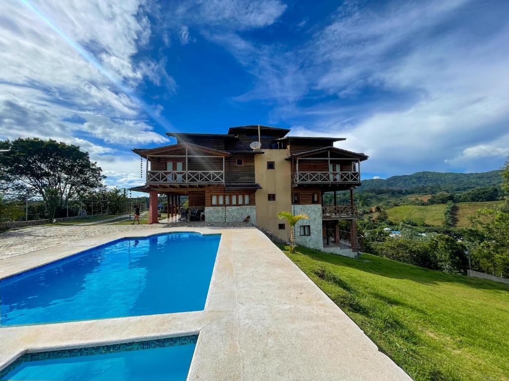 uma casa com piscina em frente a uma casa em Villas Las Neblinas em Constanza