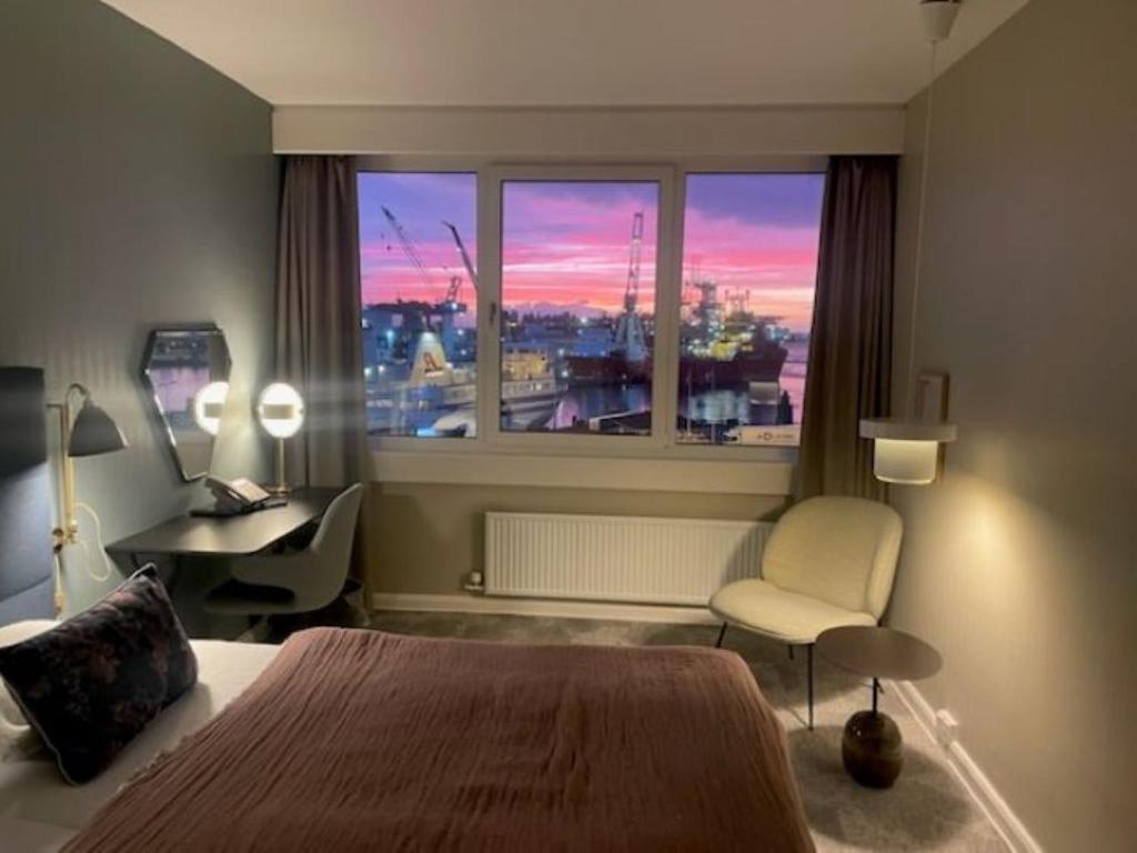 a bedroom with a bed and a desk and a window at Hotel Jutlandia in Frederikshavn