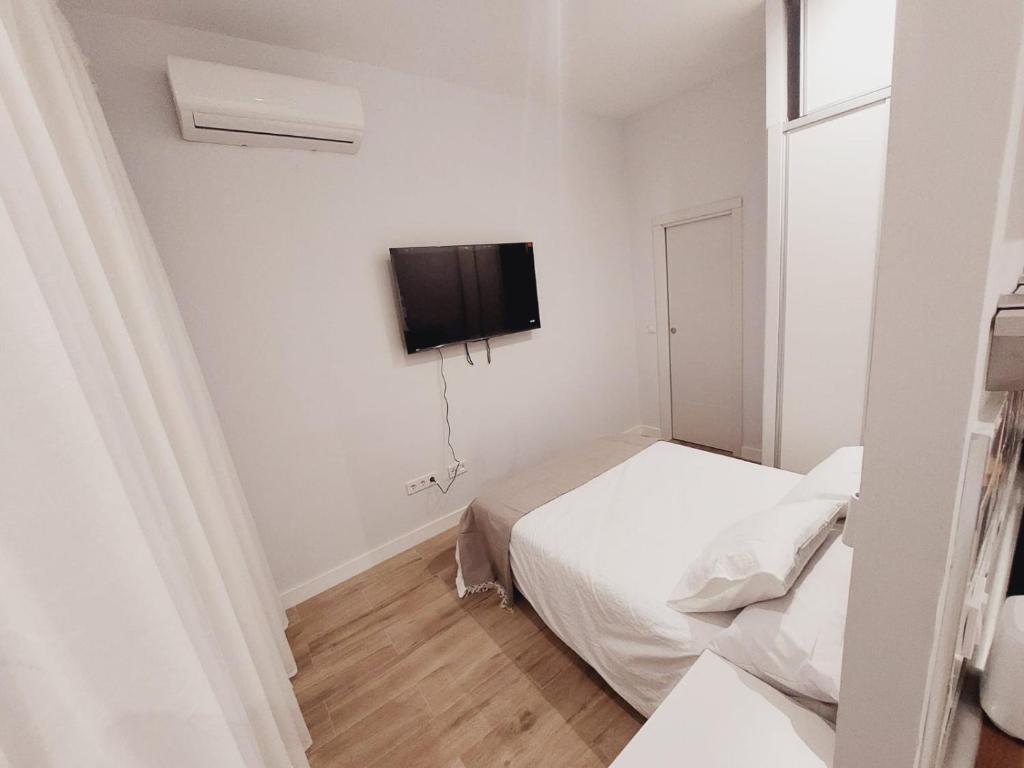 a bedroom with two beds and a tv on the wall at Lofts IFEMA in Madrid