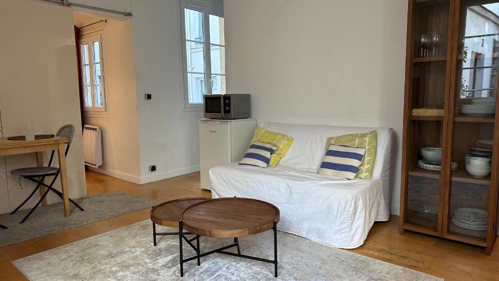 un salon avec un canapé blanc et une table dans l'établissement Haut-Marais Joli appartement., à Paris