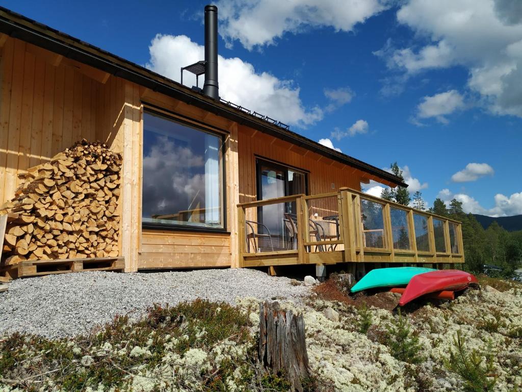 a house with a pile of fire wood next to it at Hytte ved Tunhovdfjorden in Tunhovd